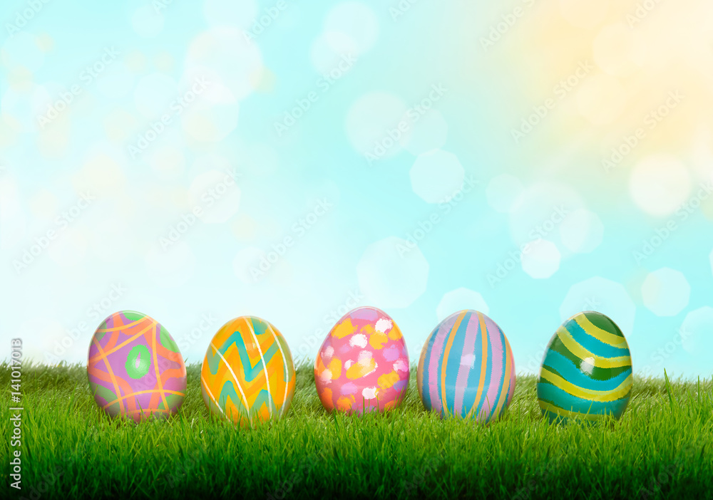 Colourful painted Easter Eggs on green grass and blurred garden and blue sky background.