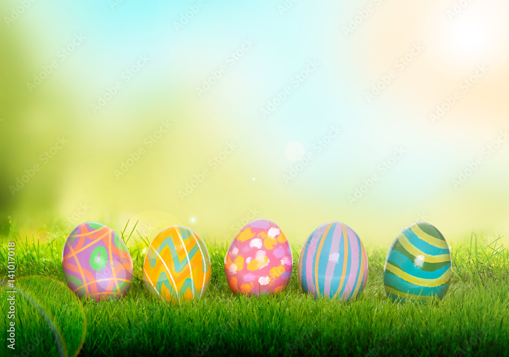 Colourful painted Easter Eggs on green grass and blurred garden and sky background.
