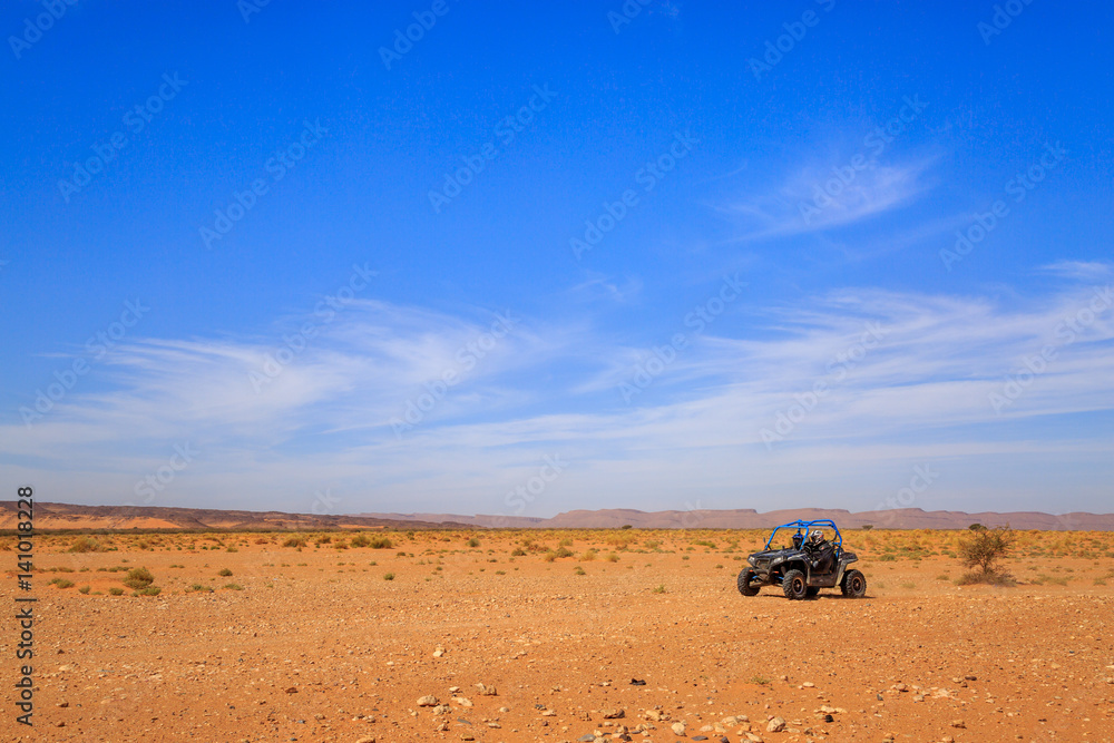 Merzouga, Morocco - Feb 26, 2016: Side view on blue Polaris RZR 800 with it's pilots in Morocco desert near Merzouga. Merzouga is famous for its dunes, the highest in Morocco. - obrazy, fototapety, plakaty 