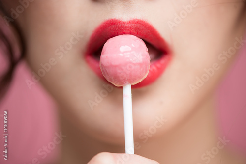 Close up of beautiful asian woman eating heart shape lollipop.