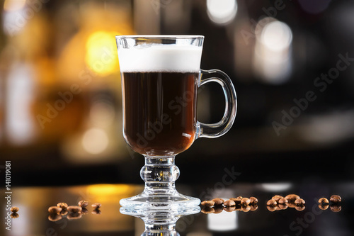 Closeup glass of irish coffee cocktail at bright bar counter background. photo