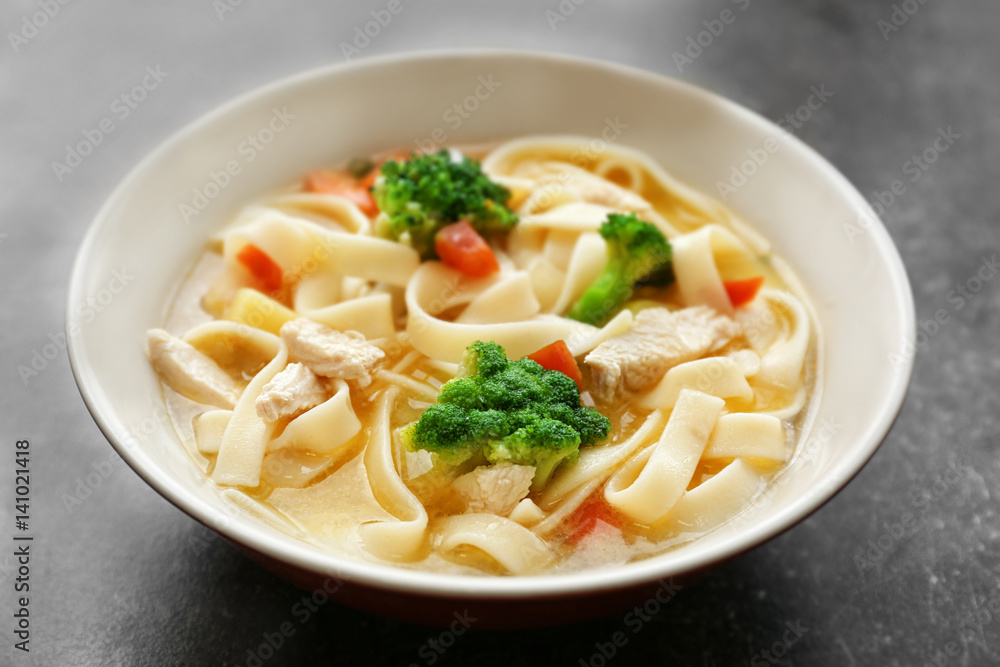 Chicken noodle soup in bowl on grey background