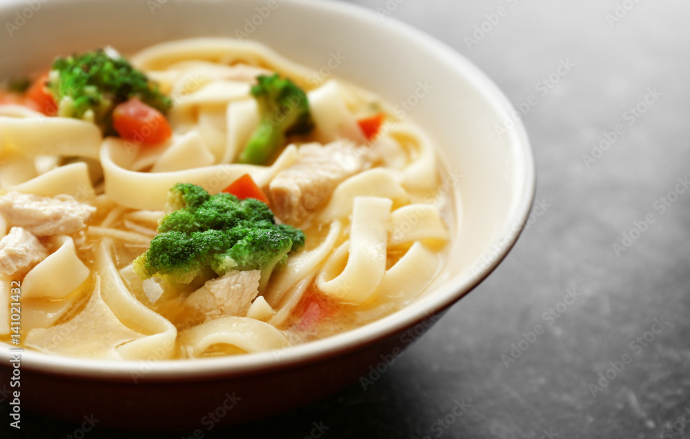 Chicken noodle soup in bowl on grey background