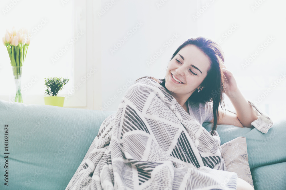 Young relaxed happy woman while sitting on comfortable sofa, home