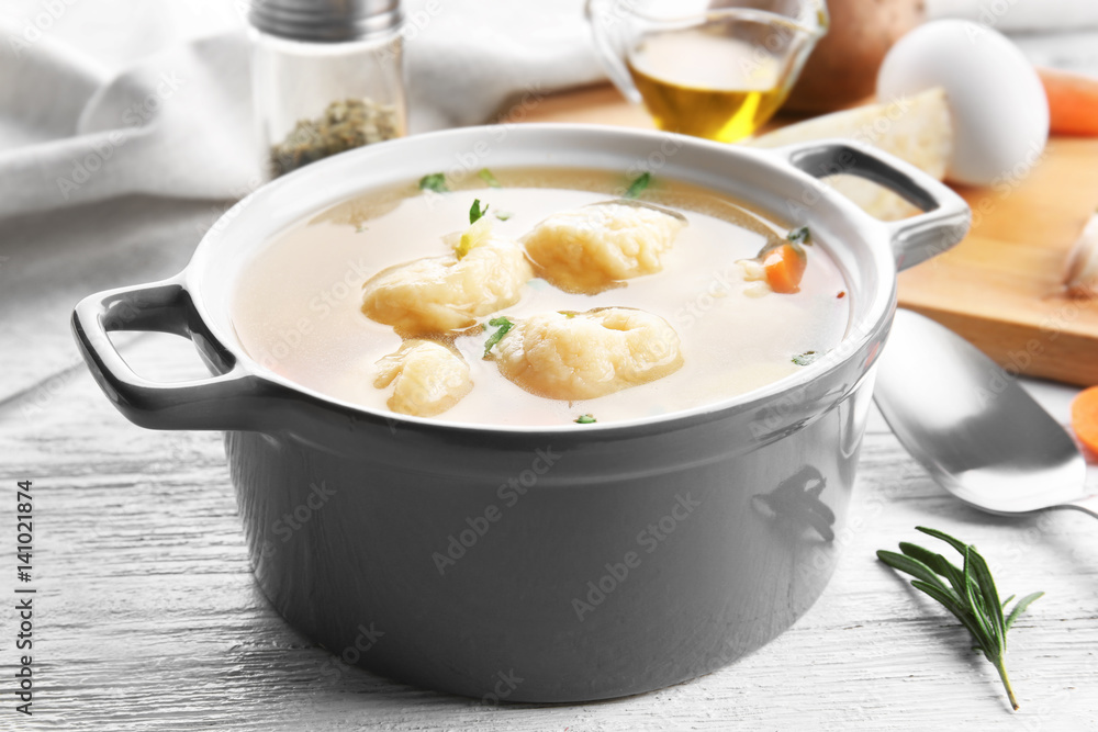 Ceramic pan with delicious chicken and dumplings on light wooden table Ceramic pan with delicious chicken and dumplings on light wooden table