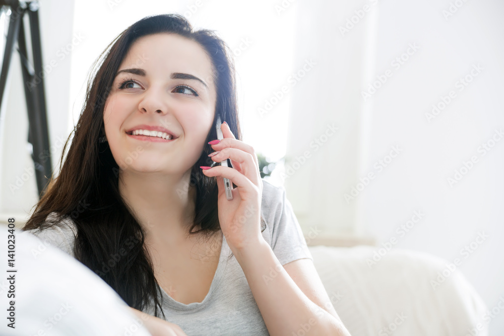 Young woman talking on phone while sitting on comfortable sofa at home Young woman talking on phone while sitting on comfortable sofa at home