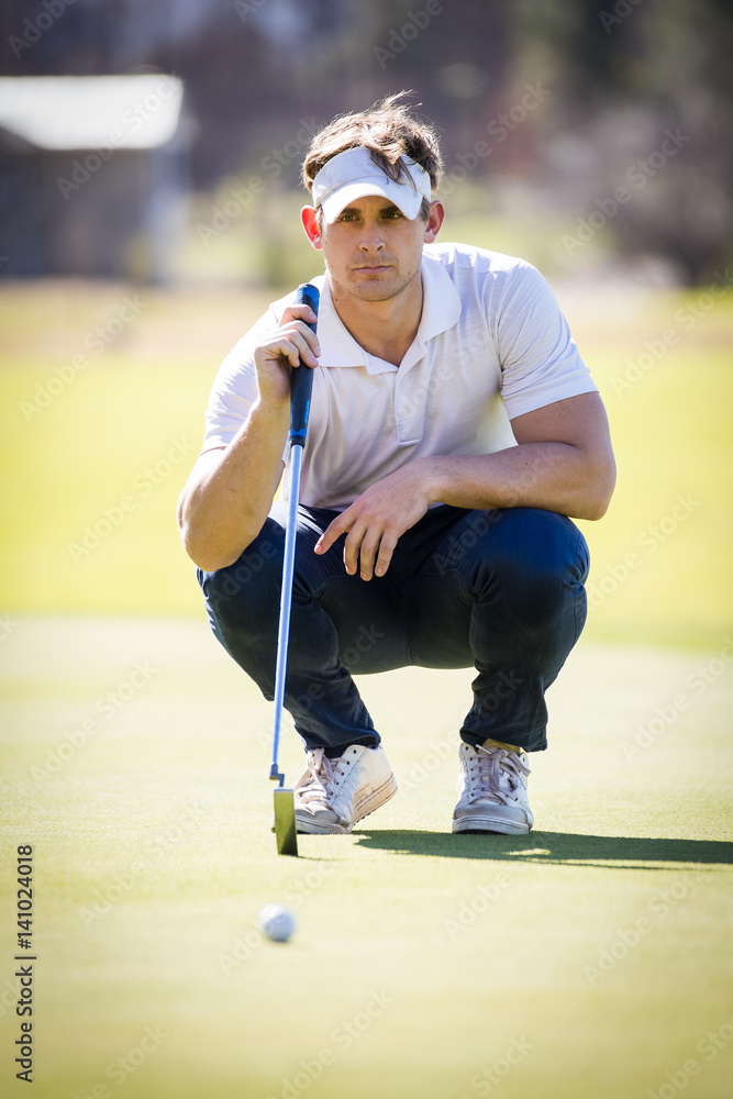 Close up view of a golfer planning his shot to the pin on a green on a bright sunny day.
