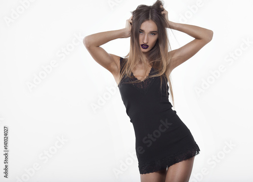 Beautiful young brunette woman in a black leather dress. Perfect body and figure. Elegant and sexy dress. Long legs. Fashion portrait.