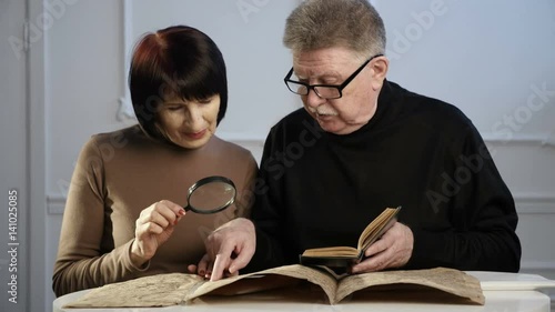 Two senior people explore some old Jewish manuscript, using a hand lens and a bo