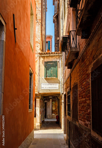 Narrow street among old colorful brick houses in Venice. Veneto, Italy