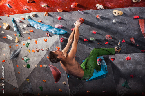 man practicing rock-climbing on a rock wall indoors