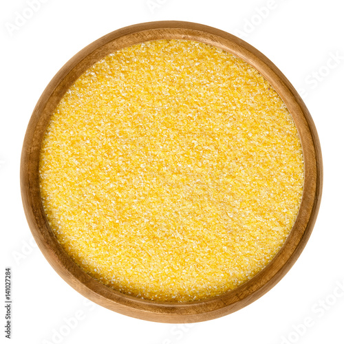 Cornmeal in wooden bowl. Raw uncooked meal, medium ground from dried maize. Common stable food. Boiled cornmeal is called polenta. Isolated macro food photo close up from above on white background. photo