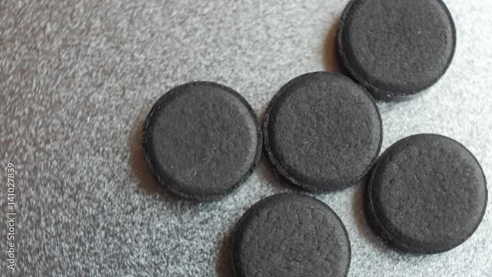 Closed up Activated charcoal carbon pills turning on a metal background. Top view. Closed up Activated charcoal carbon pills turning on a metal background. Top view.