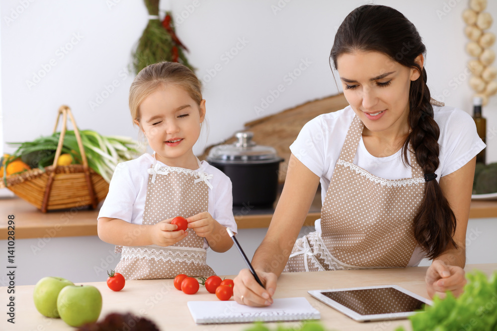 Happy family in the kitchen. Mother and child daughter cooking holiday pie or cookies for Mothers day, casual lifestyle photo series in real life interior Happy family in the kitchen. Mother and child daughter cooking holiday pie or cookies for Mothers day, casual lifestyle photo series in real life interior