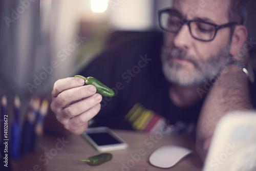 Creative Art Director looks at single green pepper to ad spice to his campain photo
