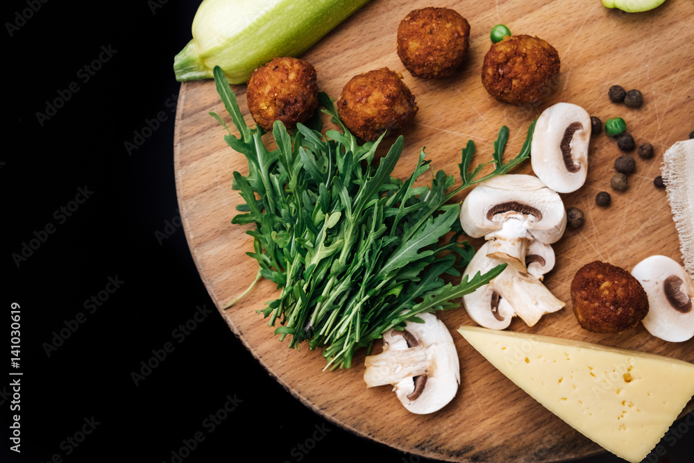 Vegetarian falafel and fresh green vegetables and mushrooms on a wooden board Vegetarian falafel and fresh green vegetables and mushrooms on a wooden board