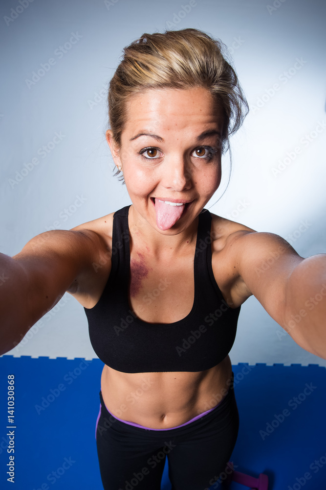 Beautiful female fitness model resting after a hard training session and taking a selfie for social media Beautiful female fitness model resting after a hard training session and taking a selfie for social media