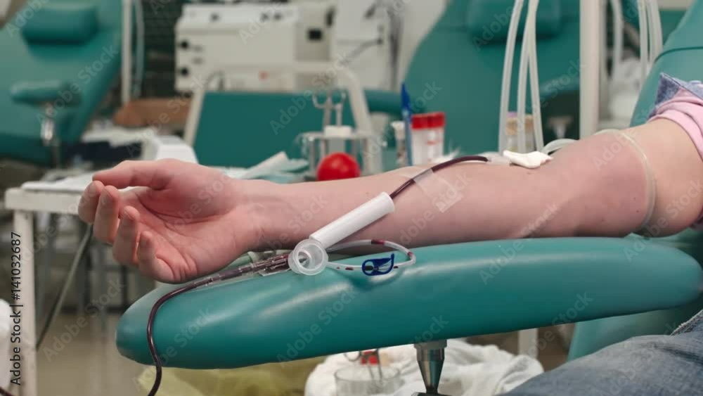 Blood bank employee untying tourniquet, taking off needle with