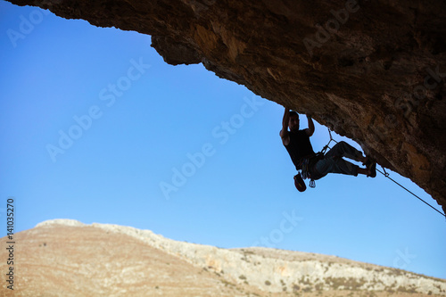Young man climbing on ceiling of cave