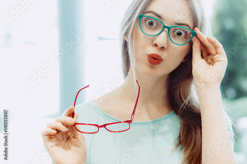 young woman trying on different pairs of eyeglasses