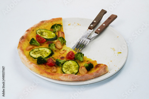 The remains of pizza on a plate with a knife and fork