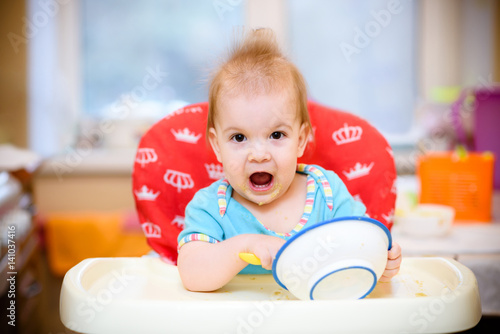 One year old child plays in the kitchen with dishes