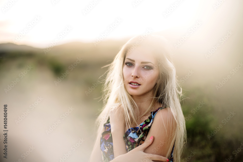 beautiful dreamy blonde girl with blue eyes in a light turquoise dress lying on the stones