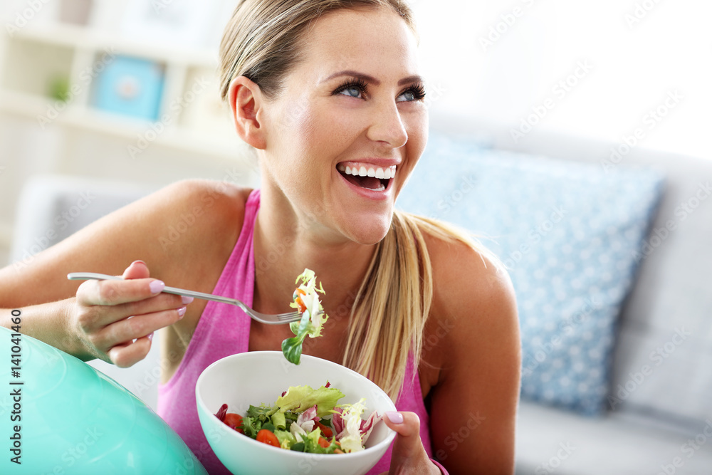 Young woman eating healthy salad after workout - obrazy, fototapety, plakaty 