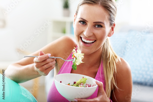 Slika na platnu Young woman eating healthy salad after workout