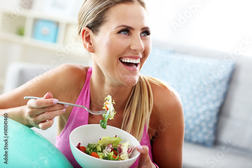 Plakat Młoda kobieta je zdrowej sałatki po treningu