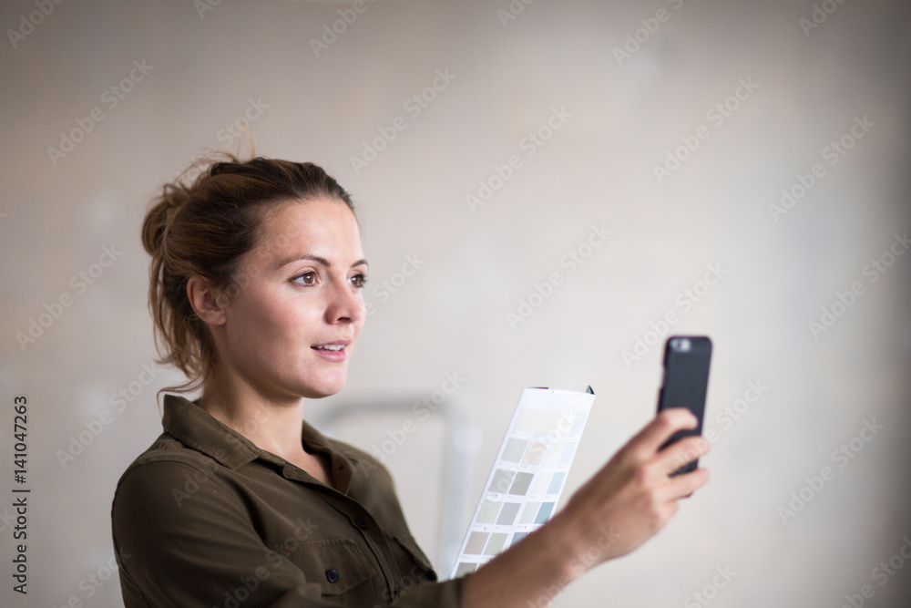 Young adult female choosing paint colors with the help of an app Young adult female choosing paint colors with the help of an app