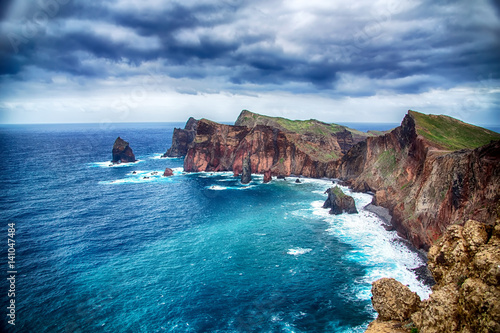 Blue ocean, rocks, windmills and cloudy sky. Portugal, Madeira Island, Ponta do Rosto