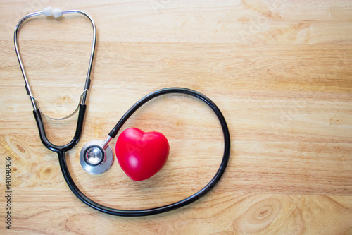 Red heart and a stethoscope on wooden table