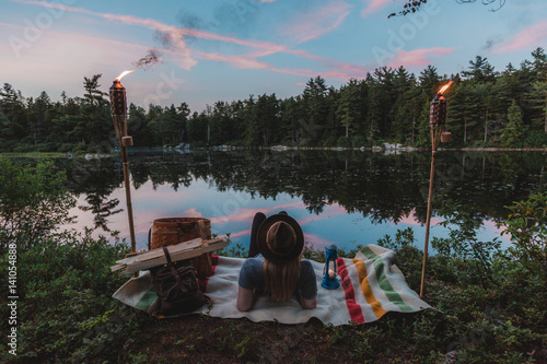 Woman relaxing beside lake, watching sunset, rear view photo