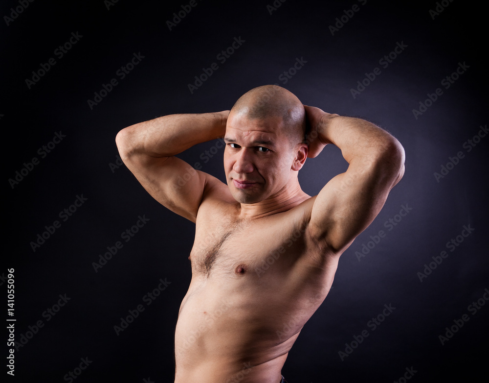 Young muscular nude man on a black background