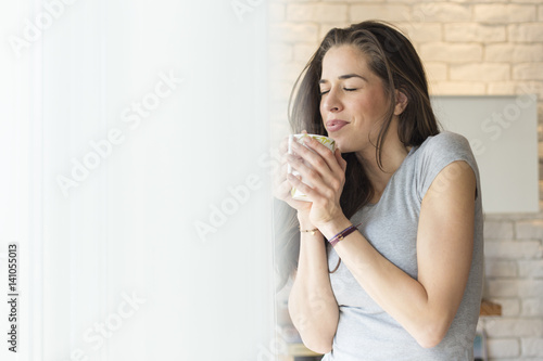 Morning coffee. Woman enjoying coffee next to window
