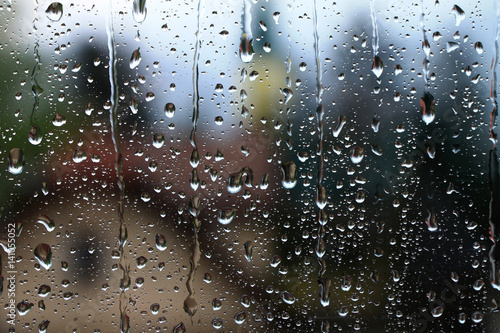 Rain drops on window with house and church in background 