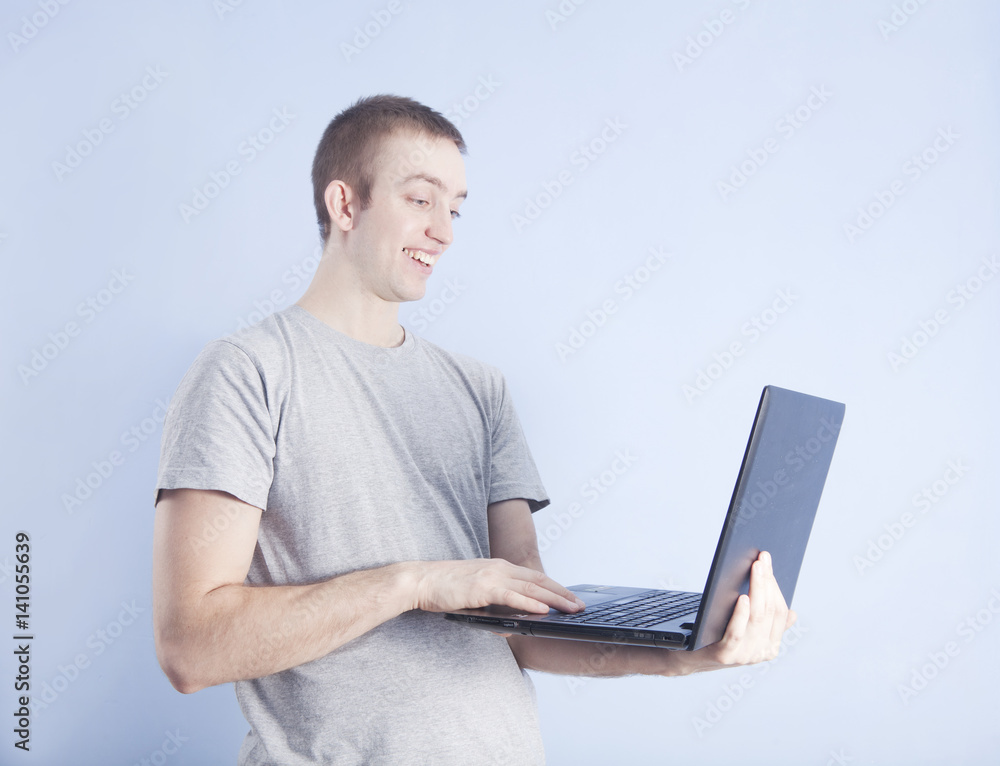 Young man with black laptop on blue background Young man with black laptop on blue background