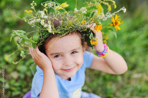 Baby girl in wreath of wild flowers and background of nature. Midsummer day. Easter. Ivan Kupala