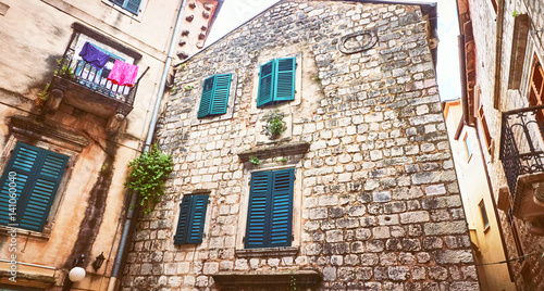 Kotor narrow small streets of  historical old town. House drying linen  bright sun blind old stone. Authentic structures. No body  tourists photo