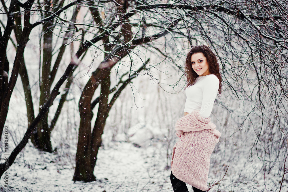 Curly brunette girl background falling snow, wear on warm knitted sweater, black mini skirt and wool stockings. Model on winter. Fashion portrait at snowy weather. Instagram toned photo. Curly brunette girl background falling snow, wear on warm knitted sweater, black mini skirt and wool stockings. Model on winter. Fashion portrait at snowy weather. Instagram toned photo.
