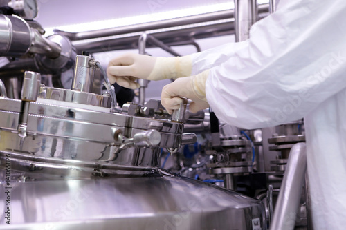 A man opens a chemical reactor. Rector of the pharmaceutical industry. The man closes the reactor. Production of granulate, suspension for tablets.