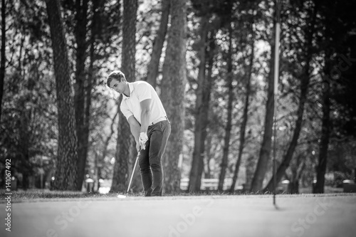 Close up view of a golfer playing a chip shot on a golf course in south africa with back light.