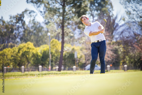Close up view of a golfer playing a chip shot on a golf course in south africa with back light.