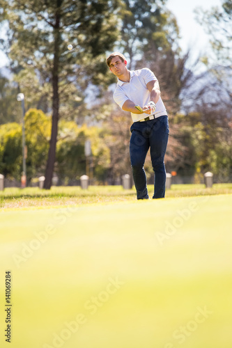 Close up view of a golfer playing a chip shot on a golf course in south africa with back light.