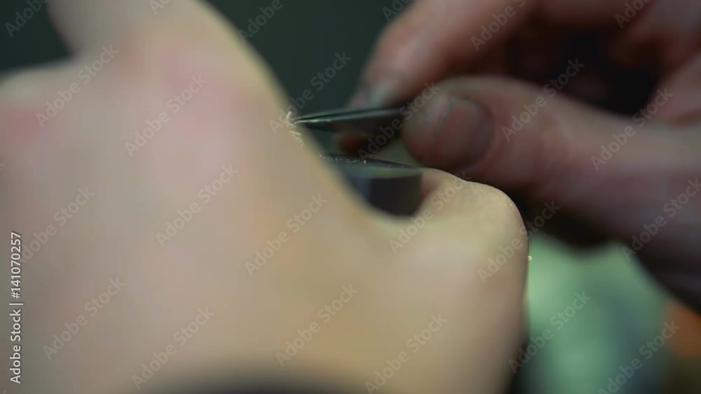 Jeweler takes gem using forceps and insert it into the silver ring close-up Jeweler takes gem using forceps and insert it into the silver ring close-up