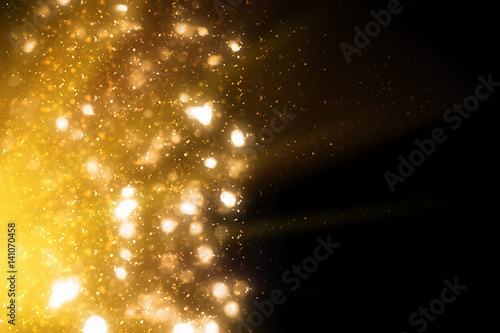 Golden abstract sparkles or glitter lights. Festive gold background. Defocused circles bokeh or particles. Template for design photo