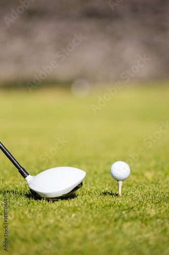 Close up view of a golf club driver on a golf course with a golf ball ready to be driven down the fairway