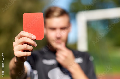 referee hands with red card on football field photo