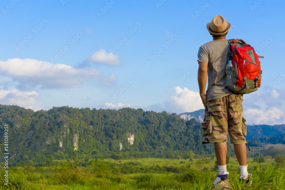 Man Asian backpack standing witon the rock and looking mountain background.Back of man
